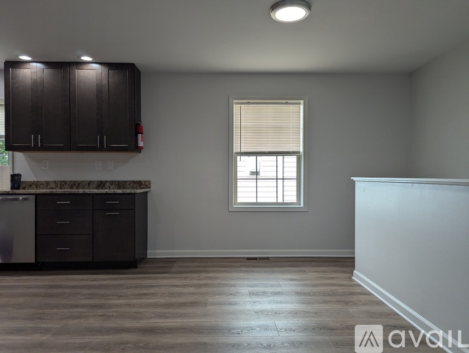 A kitchen with dark brown cabinets and a window with blinds.