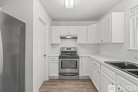 A kitchen with white cabinets and a stainless steel refrigerator.