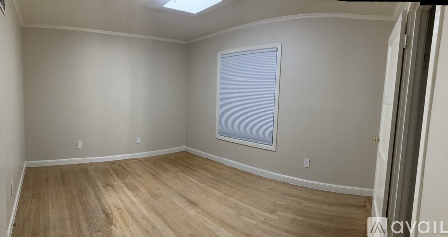 A room with wooden flooring and a window with blinds.