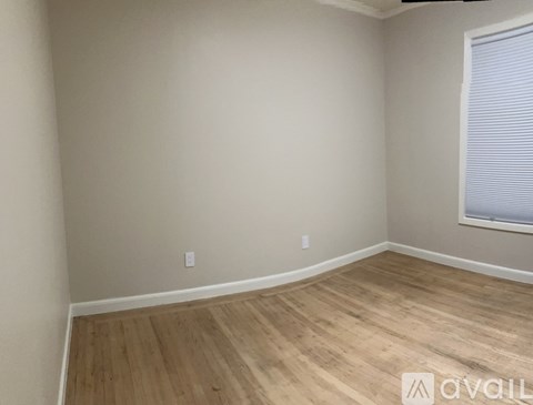 A room with wooden flooring and a window with blinds.
