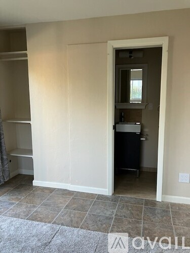 A white door is open to a room with a white wall and wooden floor.