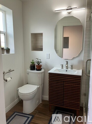 A white door is open to a room with a white wall and wooden floor.