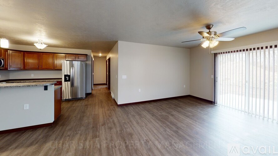 A spacious room with wooden flooring and a ceiling fan.