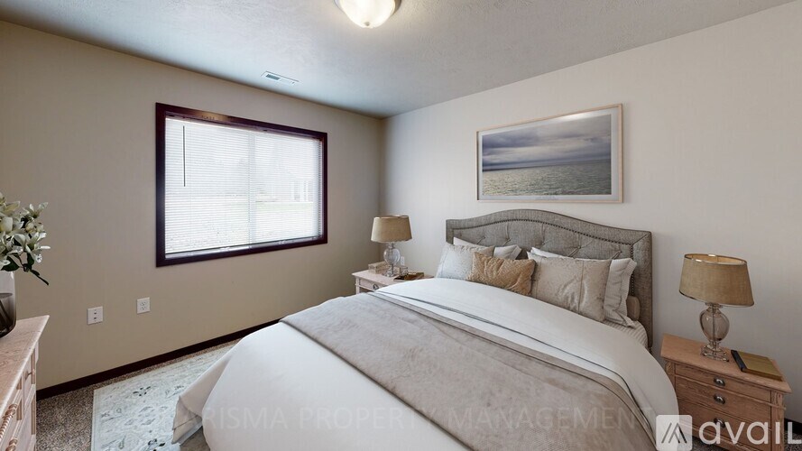 A bedroom with a large bed, a nightstand with a lamp, and a framed picture on the wall.