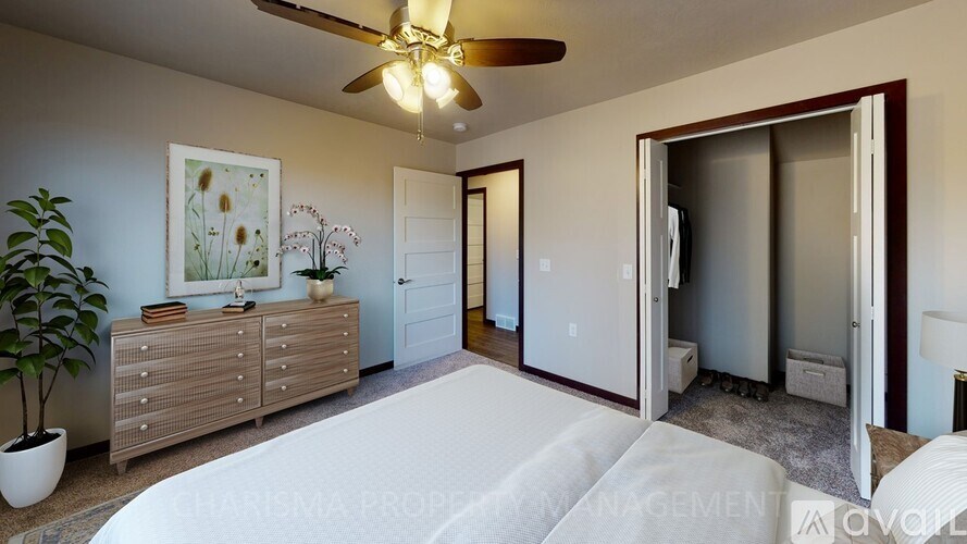 A bedroom with a bed, dresser, and a ceiling fan.