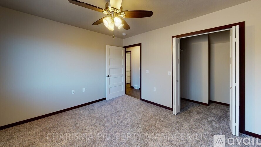 A room with a ceiling fan and two doors.