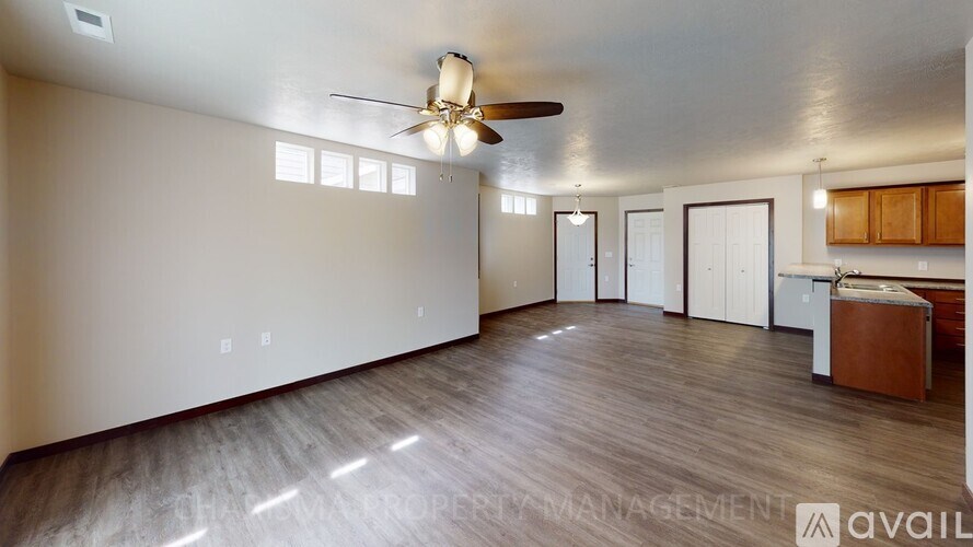 A spacious living room with a ceiling fan and hardwood flooring.