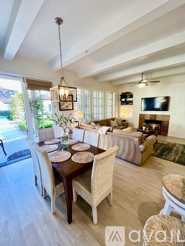 A living room with a television, a fireplace, and a dining table with chairs.