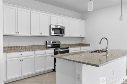 A kitchen with white cabinets and a granite countertop.