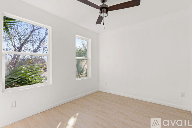 A room with a ceiling fan and two windows.