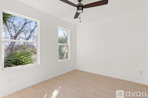 A room with a ceiling fan and two windows.