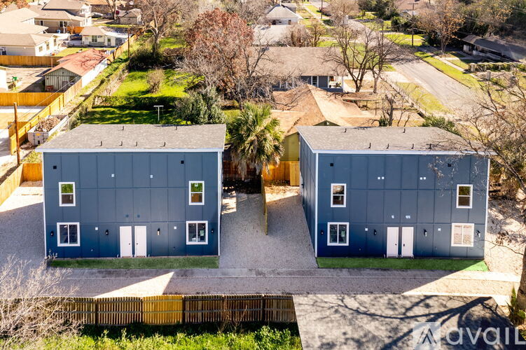 Two identical blue buildings are situated in a grassy area.