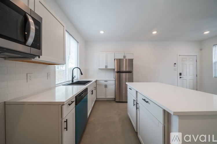 A kitchen with white cabinets and a stainless steel refrigerator.