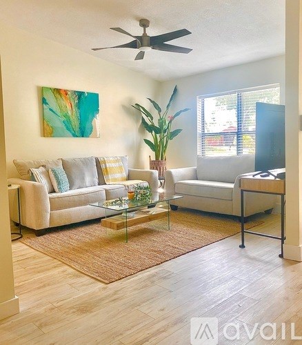 A living room with a couch, a coffee table, and a painting on the wall.