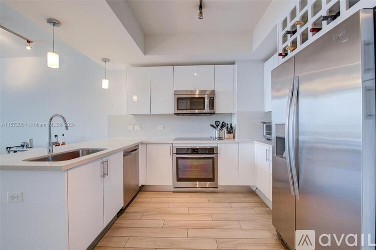 A modern kitchen with white cabinets and stainless steel appliances.