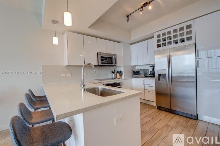 A kitchen with a white countertop and a stainless steel refrigerator.
