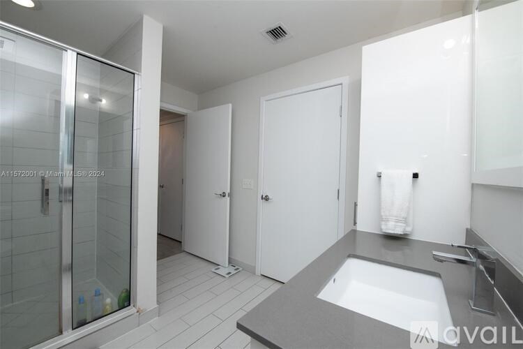 A bathroom with a glass shower door and a white sink.