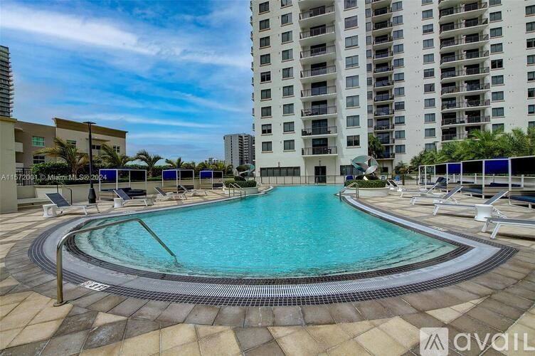 A large outdoor swimming pool surrounded by lounge chairs and umbrellas.