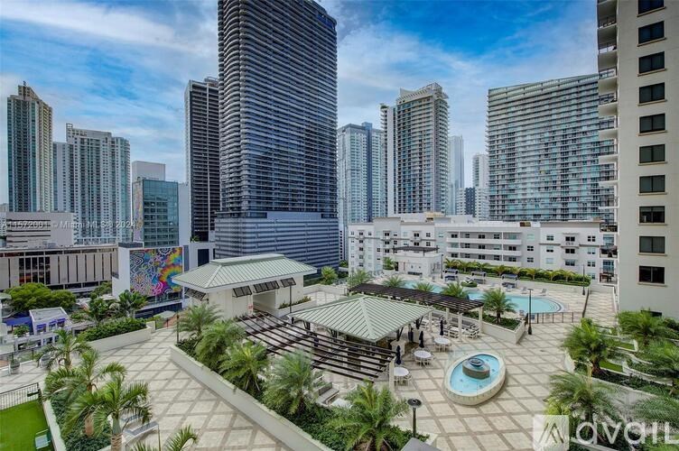 A view of a cityscape with tall buildings and a pool area in the foreground.