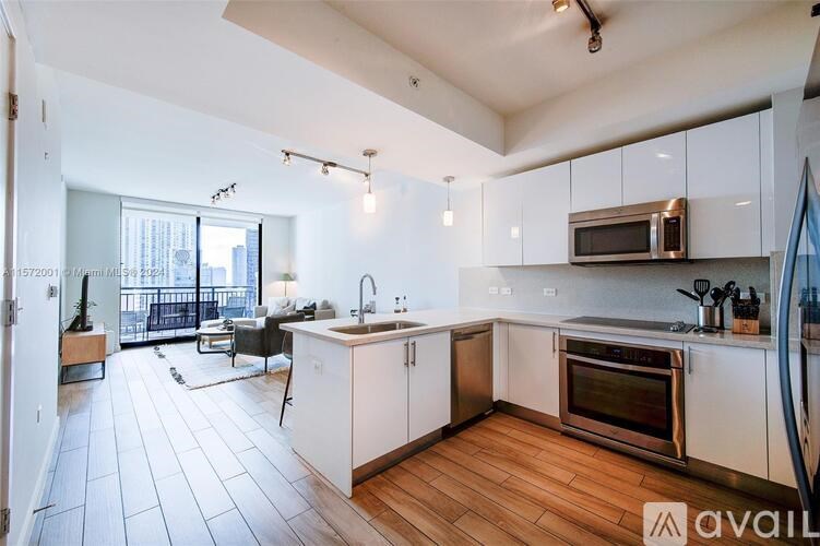 A kitchen with white cabinets and a wooden floor.
