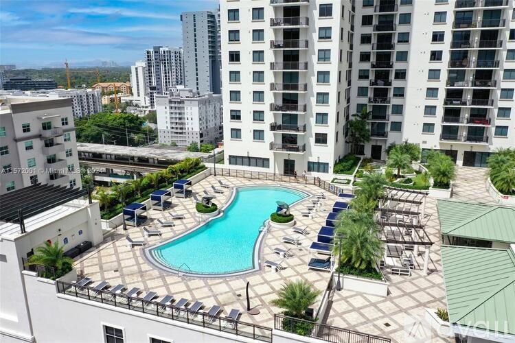 A swimming pool surrounded by sun loungers on a rooftop terrace.