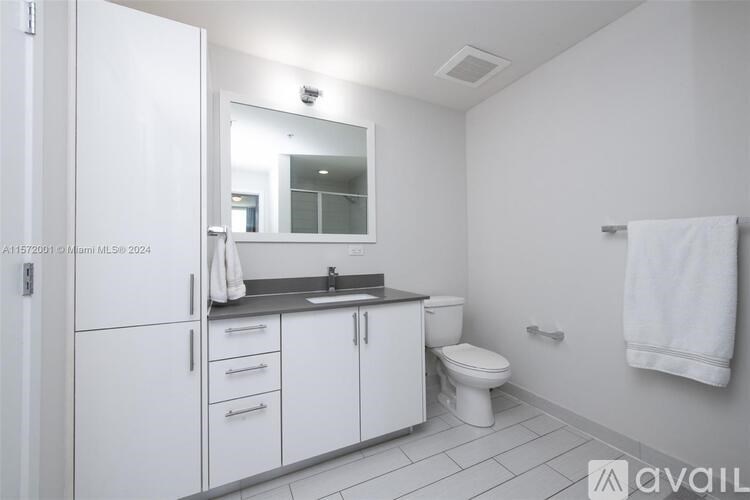 A bathroom with a white cabinet, sink, and toilet.