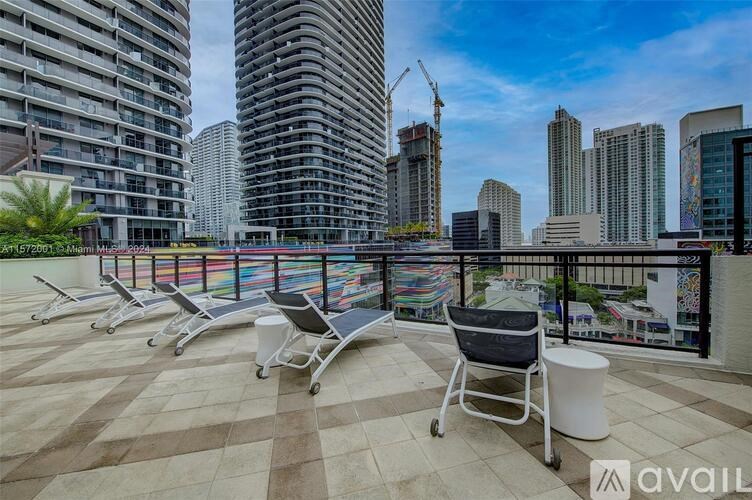 A balcony with chairs and a table overlooking a cityscape.