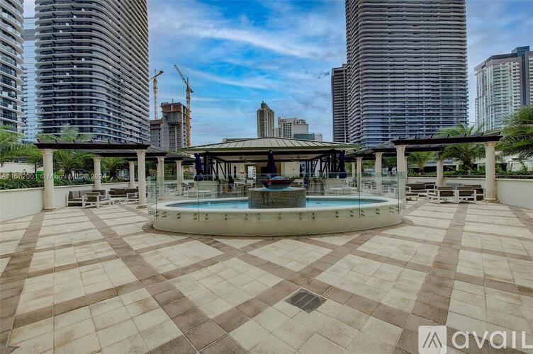 A round pool in the middle of a patio with a tiled floor and buildings in the background.