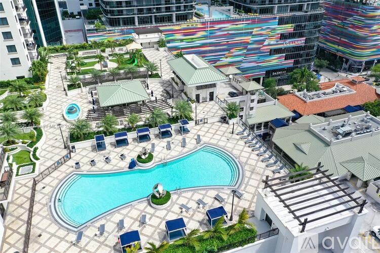 A large pool surrounded by lounge chairs and a small building.