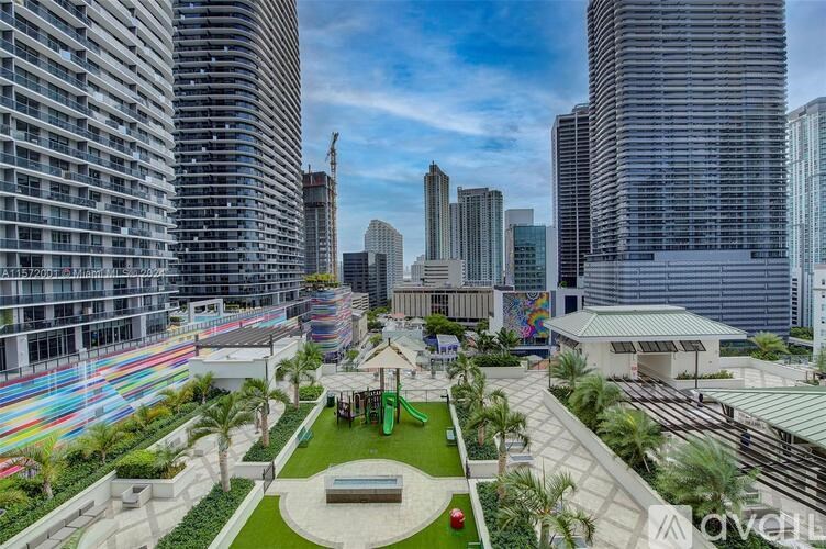 A modern cityscape with a green park area in the foreground.