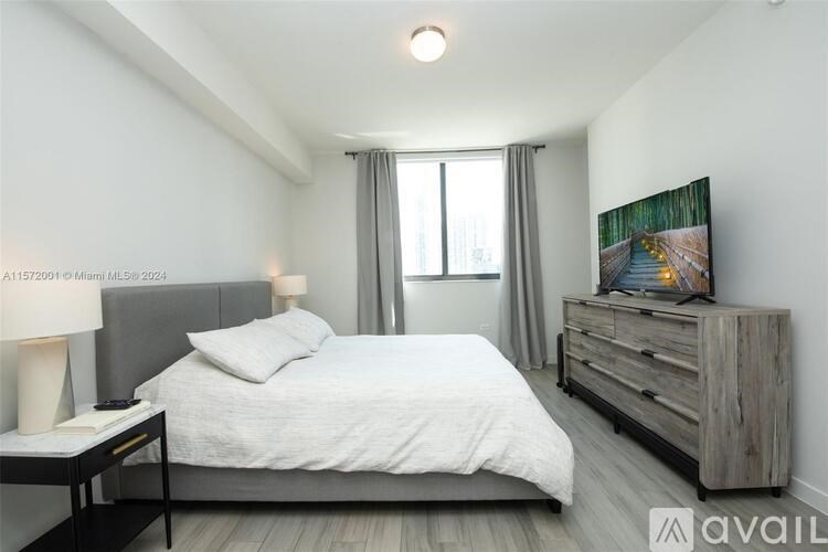 A bedroom with a bed, nightstand, and a painting on the wall.