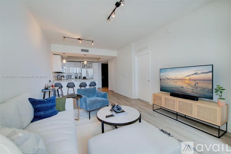 A living room with a white couch, a blue chair, and a television on a wooden stand.