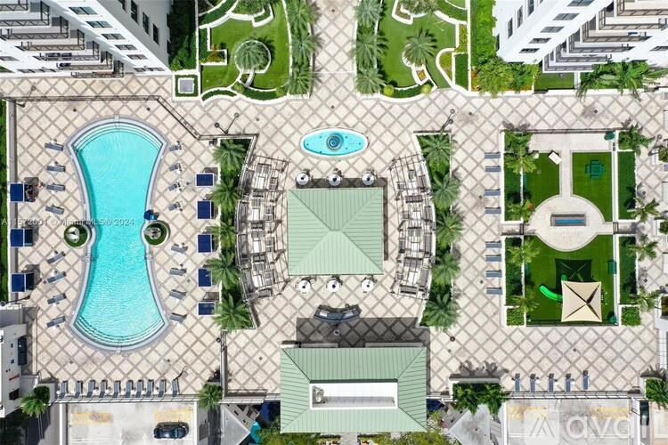 A large swimming pool is surrounded by a fence and palm trees.