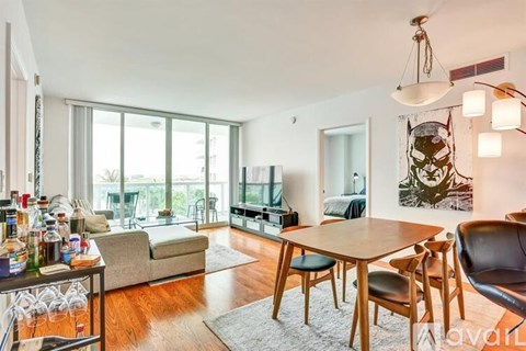 A living room with a wooden table and chairs, a sofa, and a television.