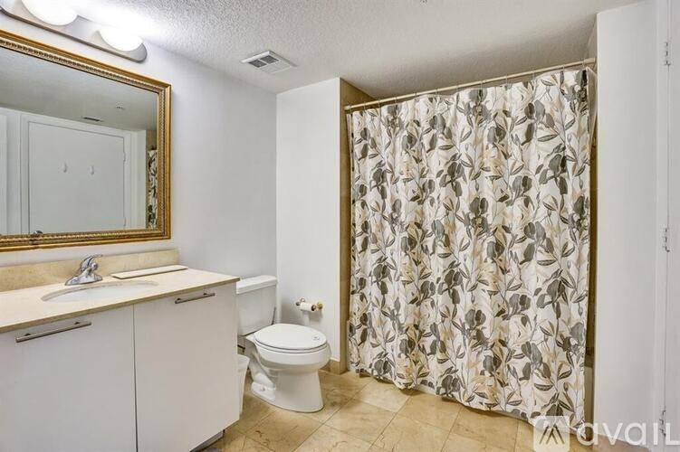 A bathroom with a toilet, sink, and shower curtain.