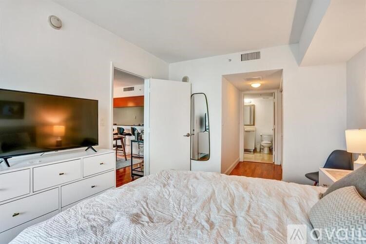 A bedroom with a bed, dresser, and television.
