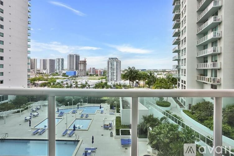 A view from a balcony overlooking a pool and apartment buildings.