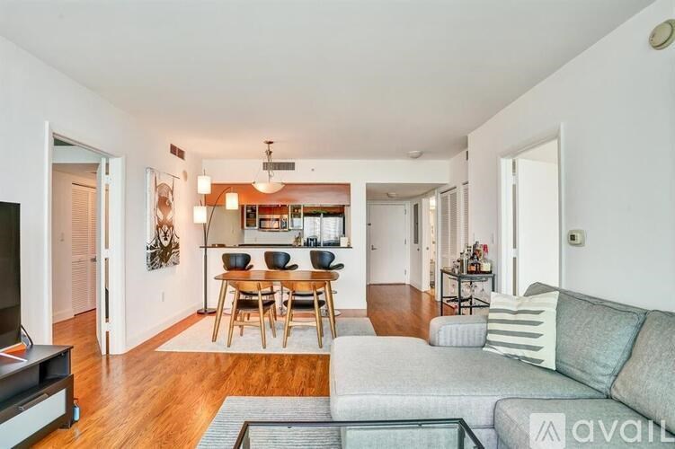 A living room with a grey couch and a wooden dining table.