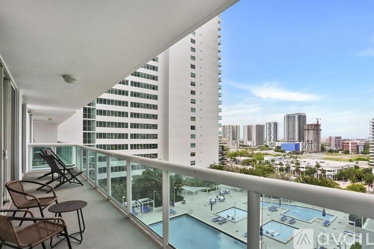 A balcony with chairs and a pool overlooks a cityscape.