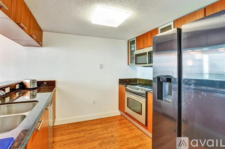 A kitchen with wooden cabinets and a stainless steel refrigerator.