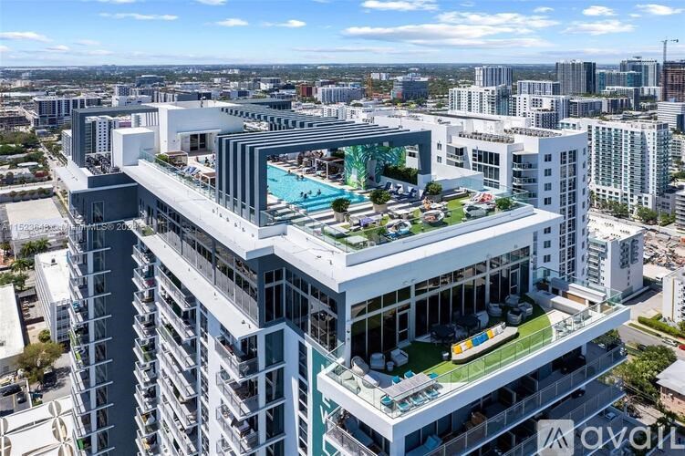 A modern multi-story building with a pool on the top floor and a green space in the middle.