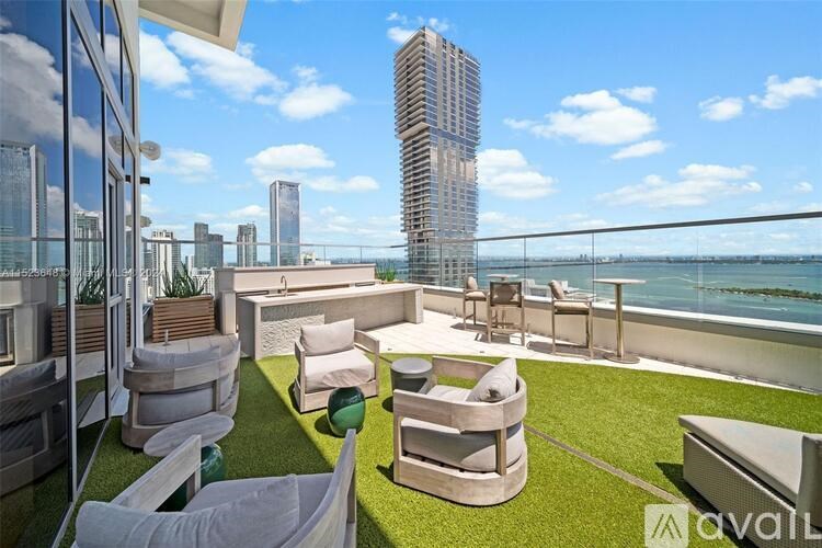 A rooftop patio with white furniture and a view of a city skyline.