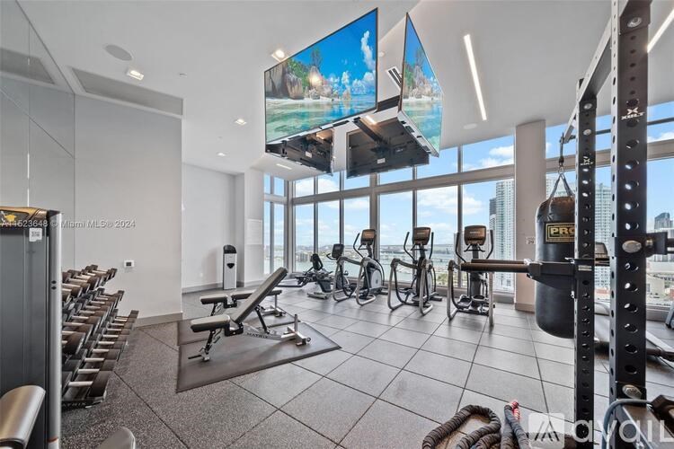 A gym with a row of treadmills and a row of stationary bikes.