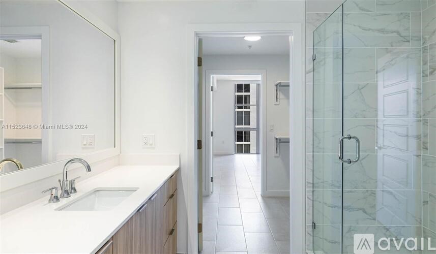 A bathroom with a sink, mirror, and glass shower door.
