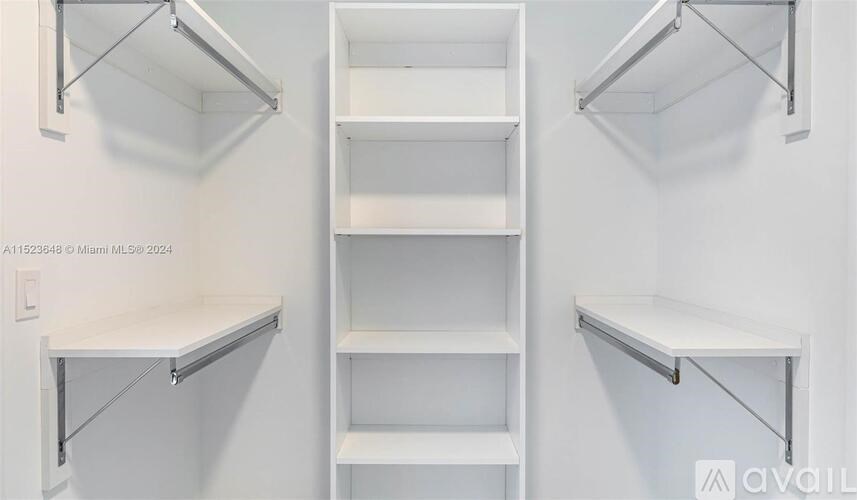 A white shelving unit with four shelves is mounted on a white wall.