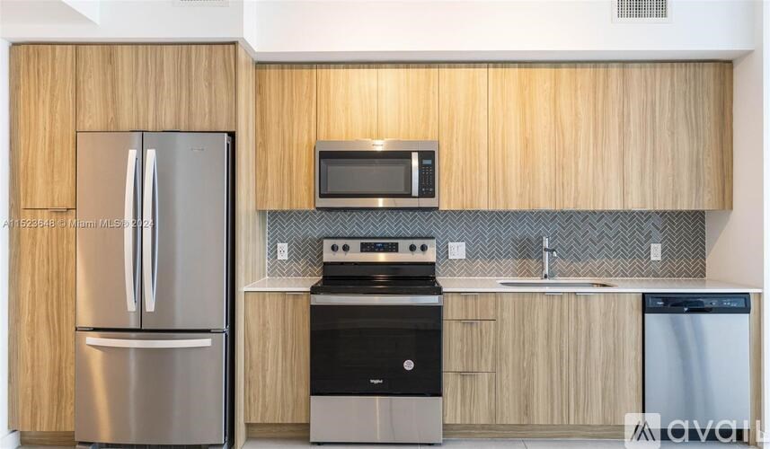 A kitchen with a refrigerator, microwave, oven, and sink.
