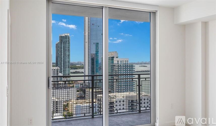 A view of a cityscape through a window with a metal railing.