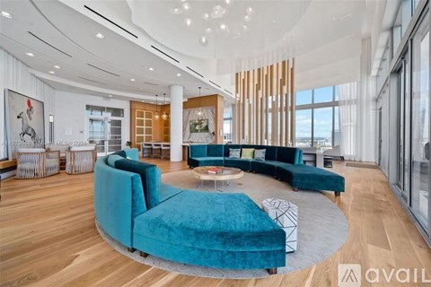 A modern living room with a blue velvet sofa and a glass coffee table.