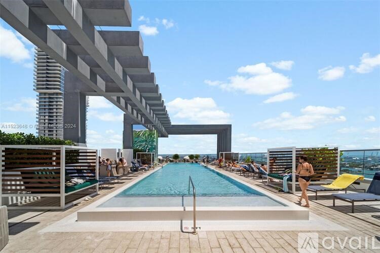 A large outdoor swimming pool with people relaxing and a building in the background.