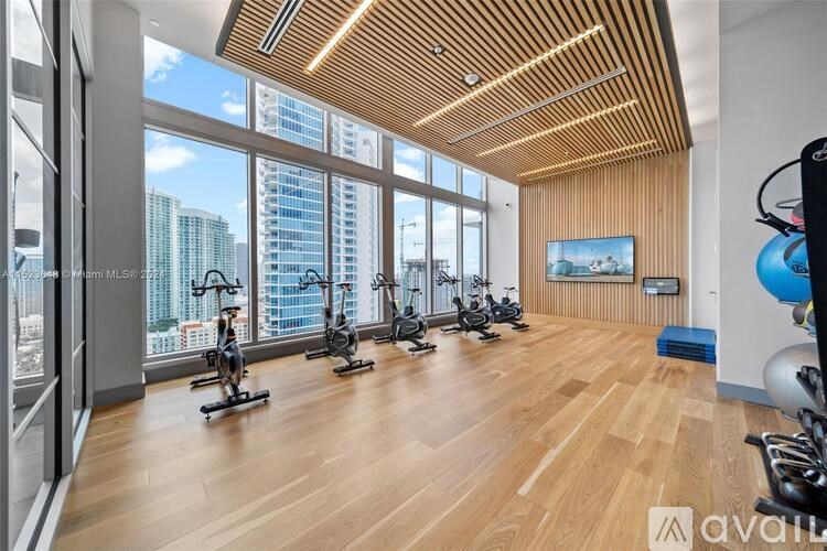 A gym with wooden floors and a row of stationary bikes.